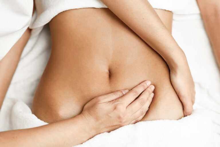 Hands massaging female abdomen