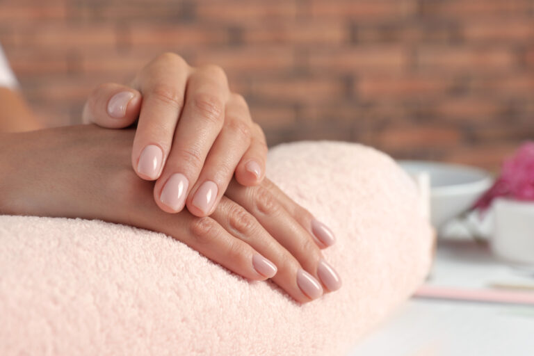 Woman showing neat manicure on towel, closeup with space for text